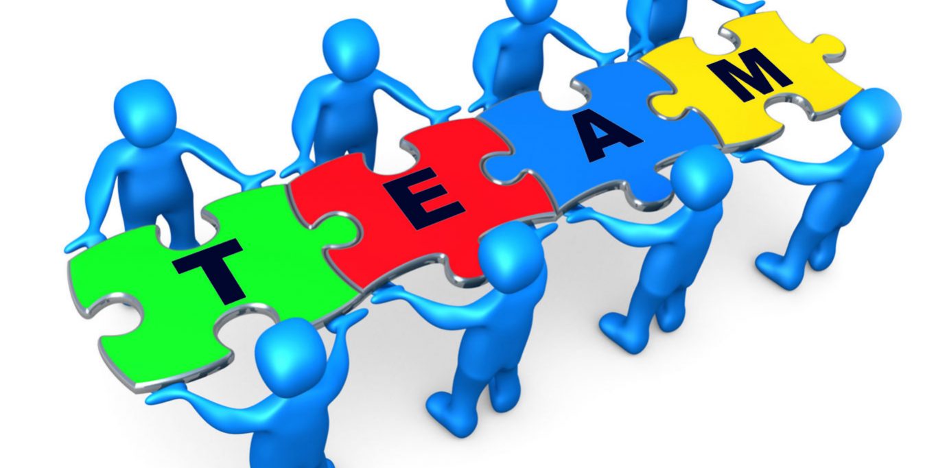 Team Of 8 Blue People Holding Up Connected Pieces To A Colorful