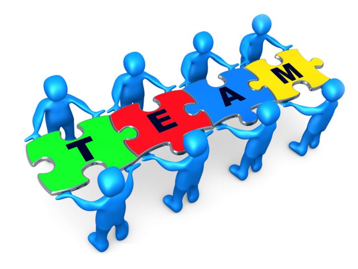Team Of 8 Blue People Holding Up Connected Pieces To A Colorful